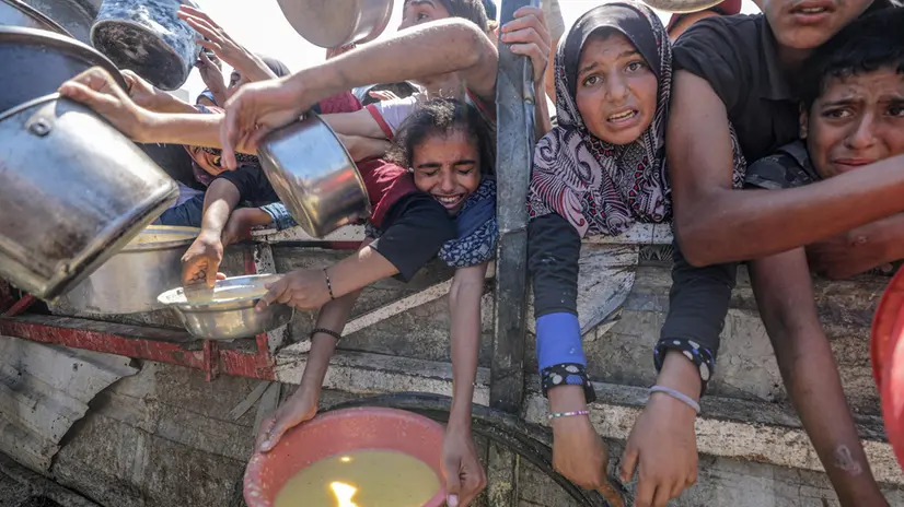 epa12282784 Internally displaced Palestinians, including children, hold pots as they receive food from a charity kitchen, in Gaza City, Gaza Strip, 04 August 2025. Humanitarian organizations have warned of an imminent food catastrophe for thousands of children, a crisis caused by severe food insecurity, a decline in health services, and ongoing restrictions on humanitarian aid and essential supplies. EPA/MOHAMMED SABER