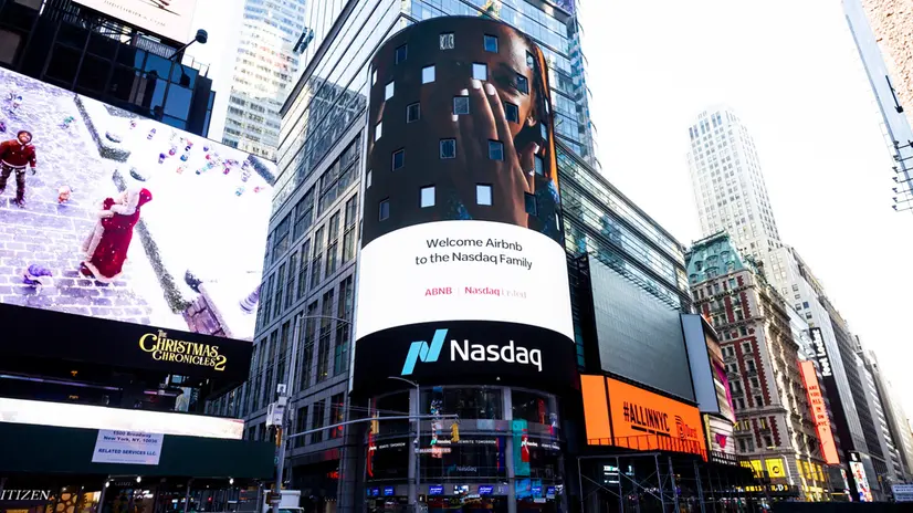 epa08875084 A video screen on the Nasdaq building shows the Airbnb logo to mark the company’s initial public offering on the stock exchange in New York, New York, USA, 10 December 2020. Shares of the company after market open were indicated to open at 149 US Dollar per share, more than double the initial price of 68 USD per share. EPA/JUSTIN LANE