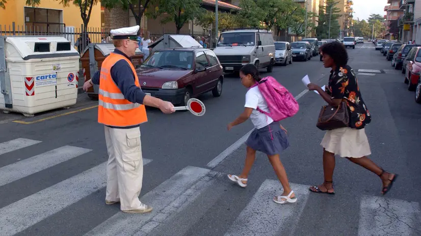 Un volontario aiuta ad attraversare un'alunna - © www.giornaledibrescia.it