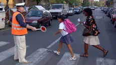 Un volontario aiuta ad attraversare un'alunna - © www.giornaledibrescia.it
