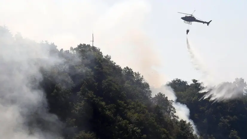 epa06124403 A helicopter spreads water over an area of a forest fire in Dajti Mountain in Tirana, Albania, 04 August 2017. The Albanian Army assists to extinguish the fire as forest fires have spread all over Albania. EPA/MALTON DIBRA