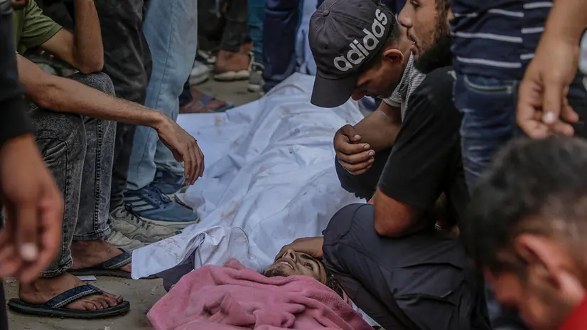 epa12274497 Internally displaced Palestinians sit around the bodies of their relatives in Al Shifa Hospital after they were shot dead at a food distribution point near Zikim in Gaza City, 31 July 2025. More than 80 Palestinians were killed on 30 July after Israeli troops opened fire at a food distribution point near Zikim, the Palestinian Ministry of Health said. EPA/MOHAMMED SABER