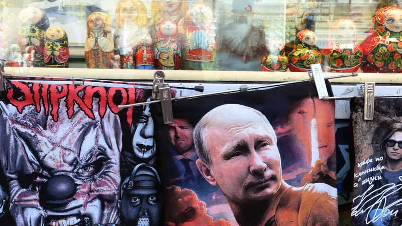 epa12298127 A t-shirt featuring portraits of Russian President Putin (C), Ukrainian President Zelensky (C-L), French President Macron (C-bottom) and former US President Biden (C-R) is on display for sale at a souvenir market in Moscow, Russia, 13 August 2025. A meeting in Alaska, USA of Putin and Trump is scheduled for 15 August 2025. EPA/MAXIM SHIPENKOV