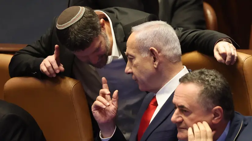 epa12255999 Israeli Prime Minister Benjamin Netanyahu (C) speaks with Israeli Finance Minister Bezalel Smotrich (L) during a plenary session to vote on a bill for applying Israeli sovereignty over the West Bank territory, at the Knesset, the Israeli parliament, in Jerusalem, 23 July 2025. The bill, submitted by the Religious Zionist Party, calls for the imposition of Israeli sovereignty over the occupied West Bank, and the use of 'Judea and Samaria' instead of West Bank in Israel's legislation. EPA/ABIR SULTAN