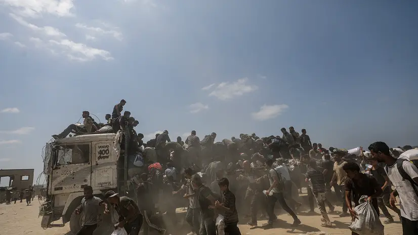 epa12290441 Internally displaced Palestinians try to grab bags of flour from an aid truck near a food distribution point in Zikim, northern Gaza Strip, 08 August 2025. Humanitarian organizations have warned of an imminent food catastrophe for thousands of children, a crisis caused by severe food insecurity, a decline in health services, and ongoing restrictions on humanitarian aid and essential supplies. EPA/MOHAMMED SABER
