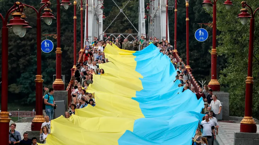 epa10143143 Ukrainians carry a giant National flag during an action called 'Ukraine is united' on a bridge in Kyiv, Ukraine, 28 August 2022 amid the Russian invasion. Ukrainians symbolically connected the left and right banks of the Dnieper river with a 430-meters-long National flag as a symbol of the people's unity in the struggle for the independence of Ukraine and that Russia-occupied territories remain Ukraine as well. Russian troops entered Ukrainian territory on 24 February 2022, starting a conflict that has provoked destruction and a humanitarian crisis. EPA/SERGEY DOLZHENKO