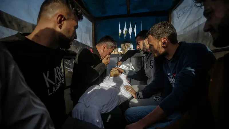 epa11790395 GRAPHIC CONTENT - Palestinians react as a father (rear) carries the body of his son during his funeral at Al Aqsa Martyrs hospital in Deir Al Balah, central Gaza Strip, 22 December 2024. According to the Palestinian Ministry of Health in Gaza, at least five Palestinians were killed following an Israeli airstrike in Al Bureij refugee camp, central Gaza. More than 45,000 Palestinians and over 1,400 Israelis have been killed, according to the Palestinian Health Ministry and the Israeli Army, since Hamas militants launched an attack against Israel from the Gaza Strip on 07 October 2023, and the Israeli operations in Gaza and the West Bank which followed it. EPA/MOHAMMED SABER -- ATTENTION EDITORS: GRAPHIC CONTENT