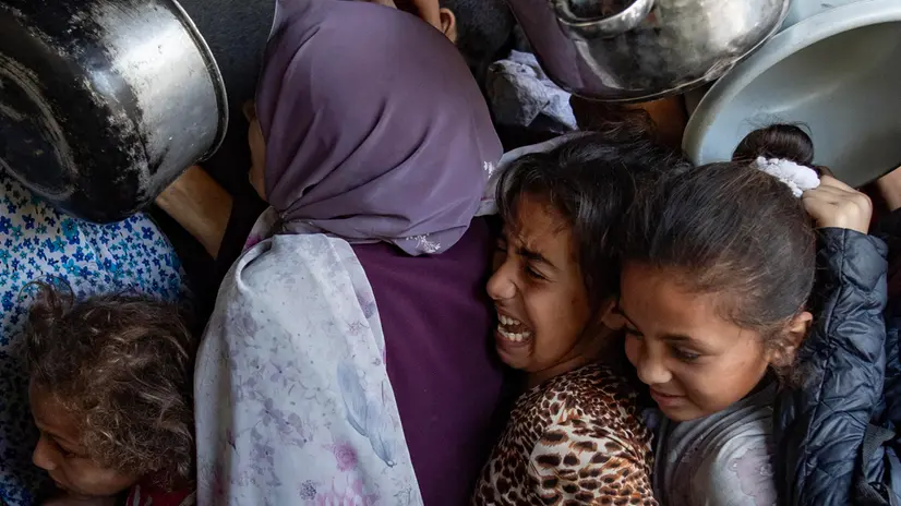 epa12122616 Hundreds of displaced Palestinians gather outside the Sokar Charity Kitchen in Gaza City to receive limited food rations,21 May, 2025. Kitchen officials say their stocks ran out today due to the suspension of humanitarian aid entering the Gaza Strip. EPA/HAITHAM IMAD