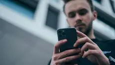 Uomo che fissa lo schermo di uno smartphone - © www.giornaledibrescia.it