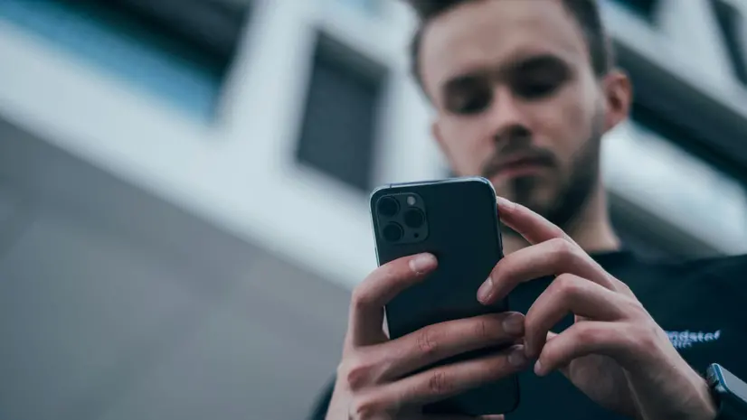Uomo che fissa lo schermo di uno smartphone - © www.giornaledibrescia.it