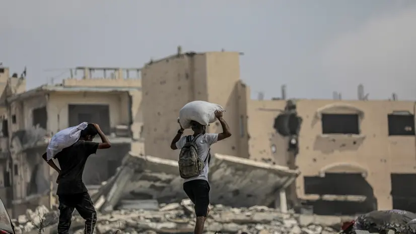 epa12290457 Internally displaced Palestinians carry bags of flour near a food distribution point in Zikim, northern Gaza Strip, 08 August 2025. Humanitarian organizations have warned of an imminent food catastrophe for thousands of children, a crisis caused by severe food insecurity, a decline in health services, and ongoing restrictions on humanitarian aid and essential supplies. EPA/MOHAMMED SABER