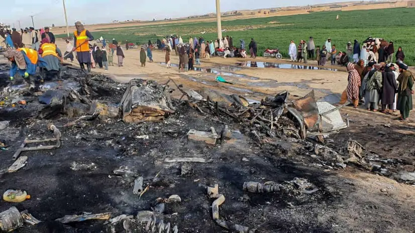 epa11226205 A handout photo made available by Afghanistan's Helmand Information Department shows security personnel and volunteers standing near the wreckage of a burned passenger bus and oil tanker after they and a motorbike collided on the Herat-Kandahar highway in Grishk district of Helmand province, Afghanistan, 17 March 2024. At least twenty-one people were killed and 38 injured on March 17 in southern Afghanistan's Helmand province after a bus collided with an oil tanker and a motorbike, provincial officials said. EPA/HELMAND PROVINCIAL INFORMATION DEPARTMENT / HANDOUT HANDOUT EDITORIAL USE ONLY/NO SALES HANDOUT EDITORIAL USE ONLY/NO SALES