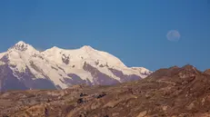 epa12287475 A view of the moon over Mount Illimani from La Paz, Bolivia, 06 August 2025. EPA/ESTEBAN BIBA
