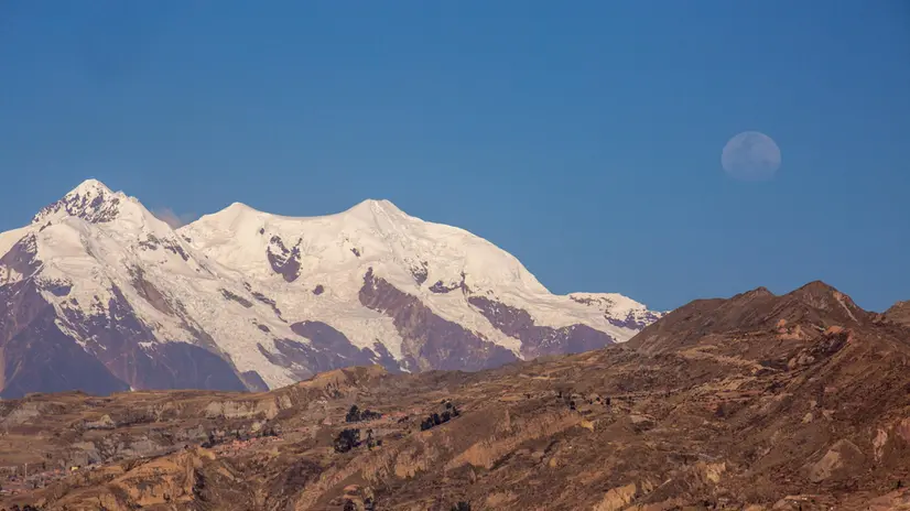 epa12287475 A view of the moon over Mount Illimani from La Paz, Bolivia, 06 August 2025. EPA/ESTEBAN BIBA
