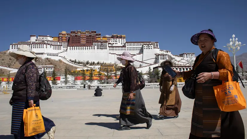 epa11994773 Women wearing traditional Tibetan clothes walk at the Potala Palace square with the Potala Palace in the background, during a government organized media tour, in Lhasa, Tibet Autonomous Region, China, 28 March 2025. The Potala Palace is a touristic spot and a pilgrimage destination for Tibetan Budism and served as the winter palace for the Dalai Lama. EPA/ANDRES MARTINEZ CASARES