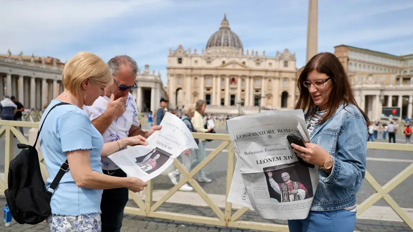 Turisti leggono l’Osservatore Romano in Piazza San Pietro, Vaticano, 09 Maggio 2025. ANSA/ANDREA SOLERO