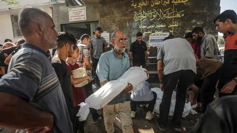 epa12255234 A man carries a shrouded body of a girl at the Al-Shifa in Gaza City, 23 July 2025. According to the Palestinian Ministry of Health in Gaza, more than 36 Palestinians were killed, tem of them from the Mushtaha family, following Israeli airstrikes last night and early today. EPA/MOHAMMED SABER