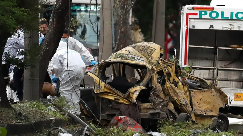 epa12315745 Members of the Criminal Investigation and Interpol Directorate (DIJIN) inspect a damaged vehicle near the Marco Fidel Suarez Military Aviation School in Cali, Colombia, 21 August 2025, after an attack. EPA/Ernesto Guzman