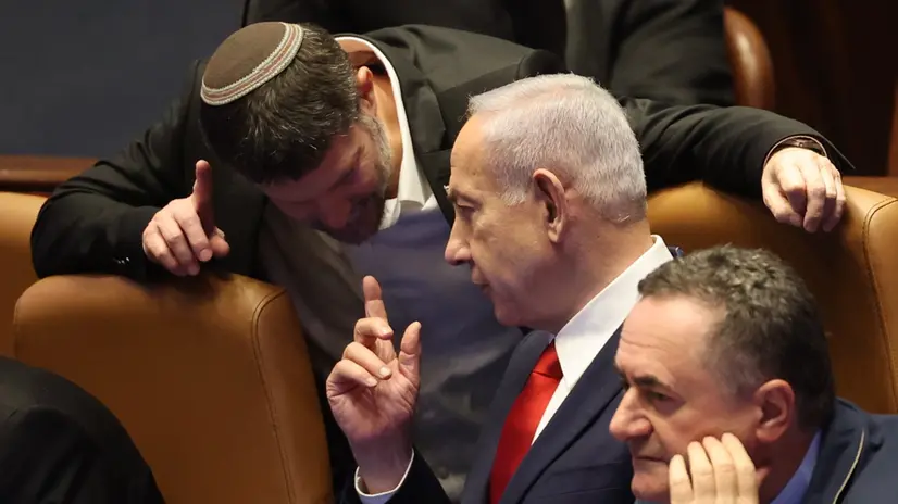 epa12255999 Israeli Prime Minister Benjamin Netanyahu (C) speaks with Israeli Finance Minister Bezalel Smotrich (L) during a plenary session to vote on a bill for applying Israeli sovereignty over the West Bank territory, at the Knesset, the Israeli parliament, in Jerusalem, 23 July 2025. The bill, submitted by the Religious Zionist Party, calls for the imposition of Israeli sovereignty over the occupied West Bank, and the use of 'Judea and Samaria' instead of West Bank in Israel's legislation. EPA/ABIR SULTAN