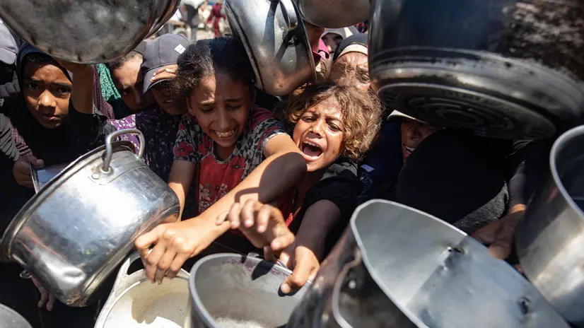 epaselect epa12317917 Palestinians queue to receive a meal from a kitchen that provides free food for displaced people in Khan Yunis, southern Gaza Strip, on 23 August, 2025. EPA/HAITHAM IMAD