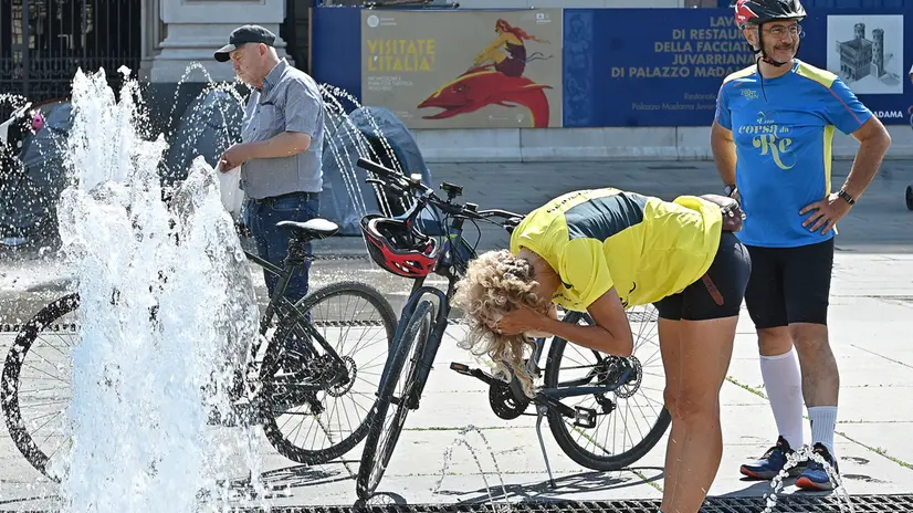 Persone cercano refrigerio dal caldo torrido nelle fonatne di piazza castello, 11 agosto 2025 ANSA/ALESSANDRO DI MARCO