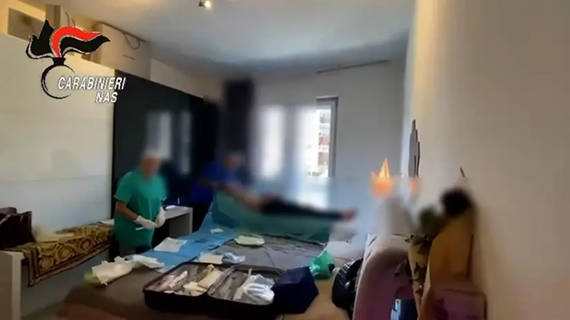Un fermo immagine tratto da un video mostra un momento dell'operazione dei Carabinieri del Nas di Roma che hanno posto agli arresti domiciliari il medico sorpreso nei giorni scorsi ad operare all'interno di una privata abitazione a Roma, e già indagato per la morte di una paziente, avvenuta a giugno, durante un intervento di liposuzione in un ambulatorio abusivo, Roma, 22 luglio 2025. ANSA/ UFFICIO STAMPA CARABINIERI +++FOTO DIFFUSA DALL'UFFICIO STAMPA - USARE SOLO PER ILLUSTRARE OGGI LA NOTIZIA INDICATA NEL TITOLO - NON ARCHIVIARE - NON VENDERE - NON USARE PER FINI NON GIORNALISTICI - NPK+++