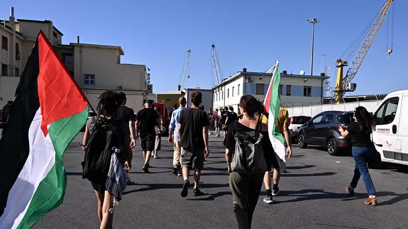 Un momento del presidio al varco di ponte Etiopia, dove i manifestanti sono entrati in porto, arrivando sino all'entrata del terminal dove sono stoccate delle armi ed esplosivi in attesa di essere imbarcati sull nave Bhari Yanbu. Dopo aver acceso e gettato fumogeni dentro il terminal, scandendo slogan co tro il traffico di armi, la manifestazione poi e' proseguita sotto la sede delle ditte che gestiscono le merci. Qui sono stati lanciati artifici pirotecnici contro il palazzo che ospita gli uffici, e dato alle fiamme cartoni e pallet sulla strada. Genova, 8 agosto 2025. ANSA/LUCA ZENNARO