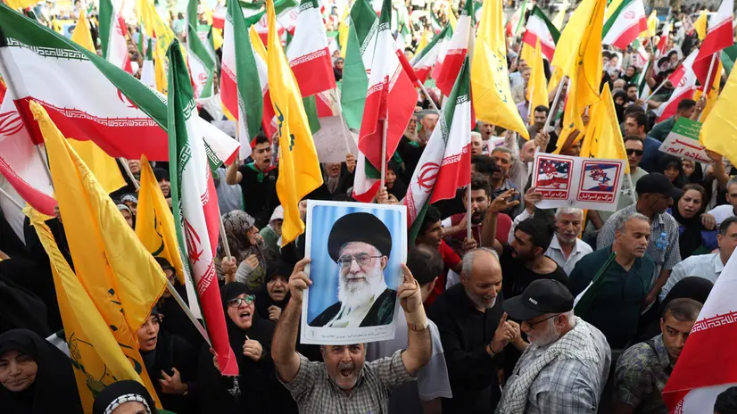 epaselect epa12194904 An Iranian holds a portrait of Iranian supreme leader Ayatollah Ali Khamenei amidst Iran’s national flags during a rally in Tehran, Iran, 24 June 2025. Israel's military accused Iran of violating a ceasefire by launching missiles into Israeli airspace. Iran's General Staff of the Armed Forces Abdolrahim Mousavi denied firing any missiles towards Israel, Iranian state media reported. EPA/ABEDIN TAHERKENAREH