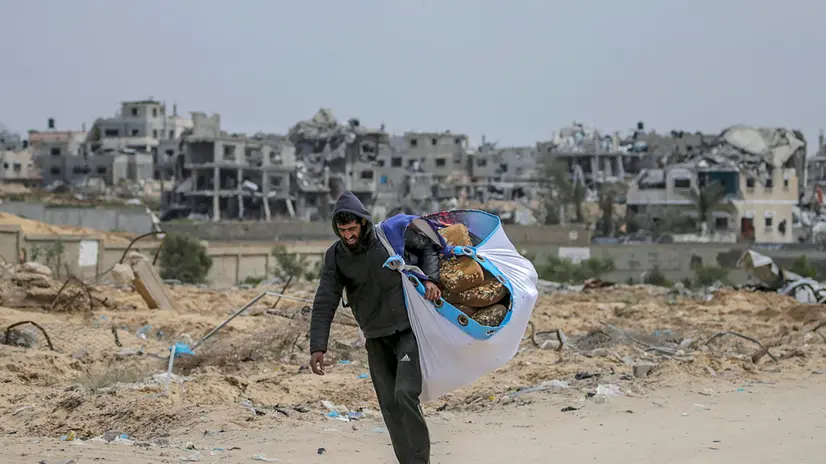 epaselect epa11241214 An internally displaced Palestinian man carrying belongings walks among debris along a street after the Israeli army asked residents of Khan Yunis town to leave their homes and head to camps in Rafah near the border with Egypt, during an Israeli military operation in Khan Yunis, southern Gaza Strip, 24 March 2024. More than 32,000 Palestinians and over 1,450 Israelis have been killed, according to the Palestinian Health Ministry and the Israel Defense Forces (IDF), since Hamas militants launched an attack against Israel from the Gaza Strip on 07 October 2023, and the Israeli operations in Gaza and the West Bank which followed it. The Israeli military stated on 24 March that it conducted an overnight operation against Hamas infrastructure and militants in the area of Al Amal, western Khan Yunis. EPA/MOHAMMED SABER