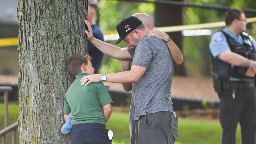 epa12327177 An adult and child take a moment while they leave the school as police respond to a shooting at the Annunciation Catholic School in Minneapolis, Minnesota, USA, 27 August 2025. According to police, two children and the gunman died and several were injured in the shooting at a Catholic primary church. EPA/CRAIG LASSIG