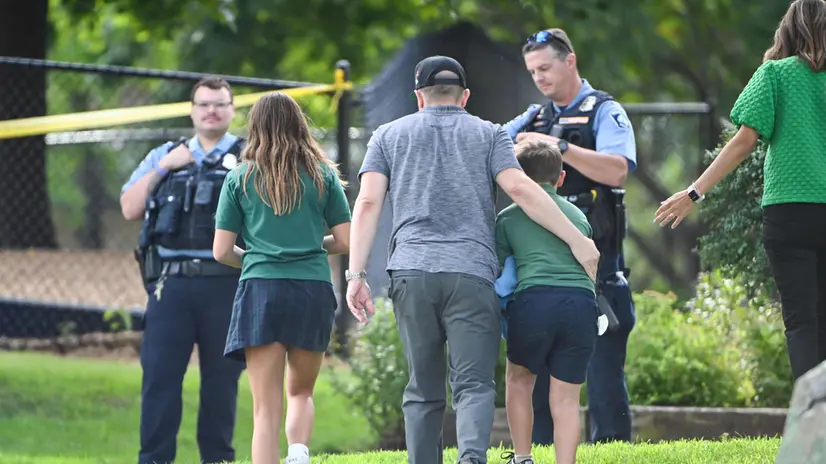 epa12327182 An adult and child take a moment while they leave the school as police respond to a shooting at the Annunciation Catholic School in Minneapolis, Minnesota, USA, 27 August 2025. According to police, two children and the gunman died and several were injured in the shooting at a Catholic primary church. EPA/CRAIG LASSIG
