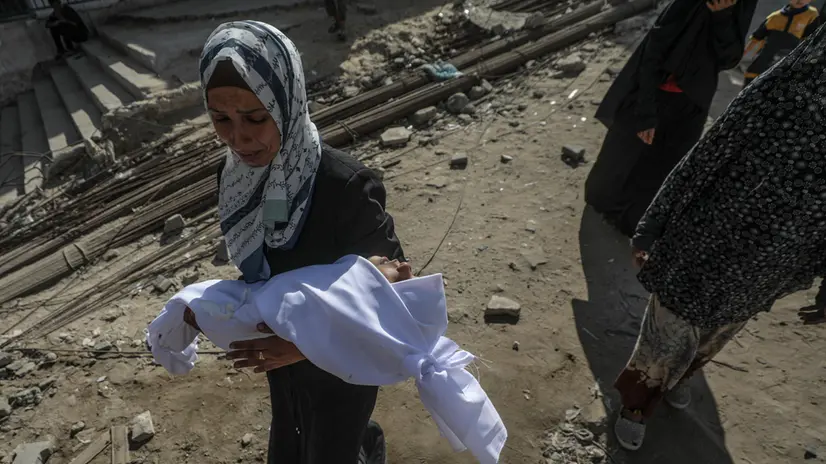 epa12333101 A Palestinian mother carries the body of her child at Al Shifa hospital in Gaza City, Gaza Strip, 29 August 2025. According to the Palestinian Ministry of Health in Gaza, more than 64 Palestinians were killed in Israeli strikes across Gaza on 28 August. EPA/MOHAMMED SABER