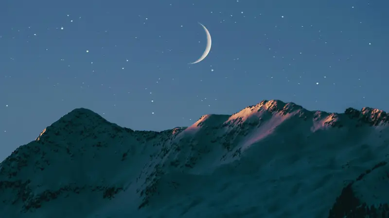 La luna e le stelle sopra le creste di una montagna