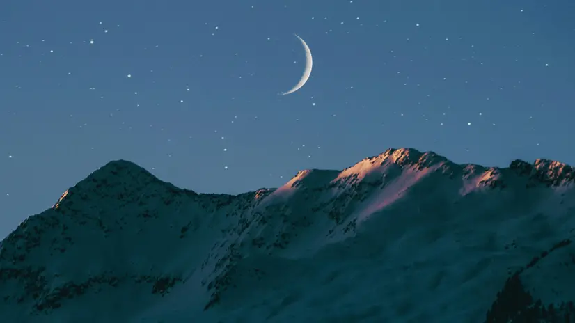 La luna e le stelle sopra le creste di una montagna