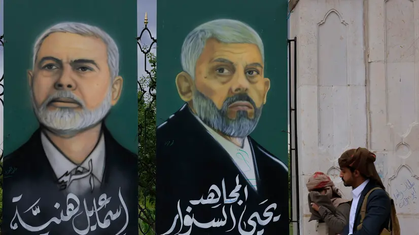 epa12324253 People walk past paintings on a fence depicting late Hamas leaders Ismail Haniyeh (L) and Yahya Sinwar (R), at a square in Sana'a, Yemen, 26 August 2025 Yemen’s Houthis have pledged to continue attacking Israel in support of the Palestinian people in Gaza, two days after Israeli airstrikes targeted several sites in the Houthi-controlled capital Sana’a, killing at least 10 people and wounding 92 others, including 21 in critical condition, according to a statement by the Houthi Political Bureau. EPA/YAHYA ARHAB