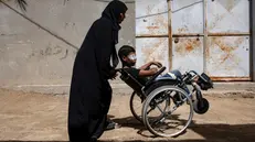 epa11616373 Palestinian teen Wahid Al-Ghalban, 13, sits on a wheelchair pushed by his mother, Rewayda, in Khan Yunis, southern Gaza Strip, 19 September 2024 (issued 20 September 2024). Wahid, an internally displaced Palestinian from Khan Yunis living in a temporary house after his home was destroyed, was injured in an Israeli military strike last April. He suffered severe injuries to the right side of his body, losing an eye, an arm and a leg. According to his family, Wahid is in desperate need of prosthetic limbs and a cornea transplant, which he is currently unable to receive in Gaza and would have to travel outside the territory to receive the necessary care. So far, he has been receiving medical care at home under the supervision of doctors from Nasser Hospital in Khan Yunis. According to UNICEF, the conflict in the Gaza Strip has taken a catastrophic toll on children, exposing them to traumatic experiences of war and consequences of which will last a lifetime. More than 11,000 children have reportedly been killed and thousands more injured in the Gaza Strip in the past 11 months, according to the latest estimate by the Palestinian Ministry of Health. EPA/HAITHAM IMAD