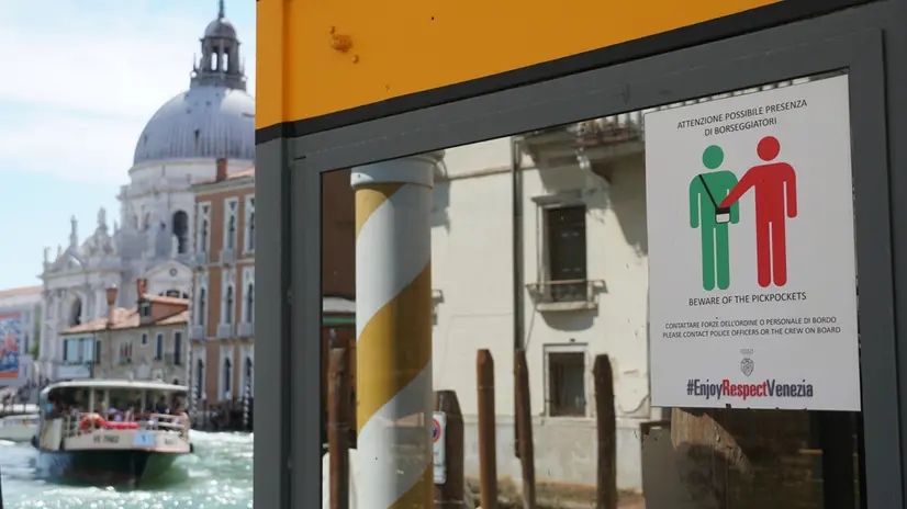 Un avviso di attenzione ai borseggiatori, affisso sul finestrone di un approdo della linea di navigazione pubblica lungo il Canal Grande, Venezia 18 luglio 2025. ANSA/ANDREA MEROLA