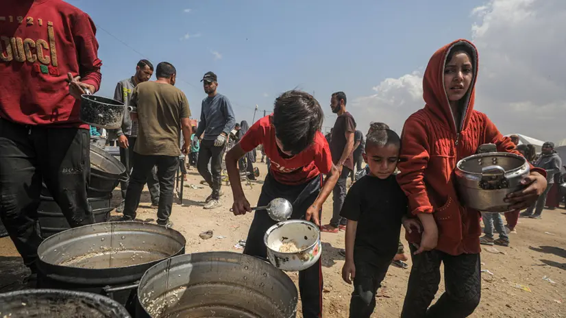 epa12068999 Internally displaced Palestinians children gather to receive a portion of food from a charity kitchen, in Jabalia, northern Gaza Strip, 02 May 2025. According to the UN Palestinian refugee agency UNRWA, over a million people across the Gaza Strip are experiencing 'high levels' of acute food insecurity, with acute malnutrition several times higher than before the war. The UN estimates at least 1.9 million people (nine in ten) are internally displaced. EPA/MOHAMMED SABER