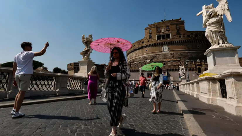 People holds umbrella to shelter from sunlight on Sant'Angelo Bridge on a hot day in Rome, Italy, 10 August 2025. ANSA/FABIO FRUSTACI