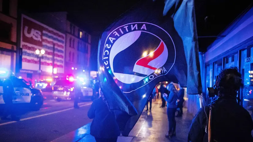 epa08799778 An Antifascist Action (Antifa) flag is seen during a protest following the US presidential election in Portland, Oregon, USA, 04 November 2020. Portland Police declared a riot after protesters began damaging businesses. EPA/CHRISTIAN MONTERROSA