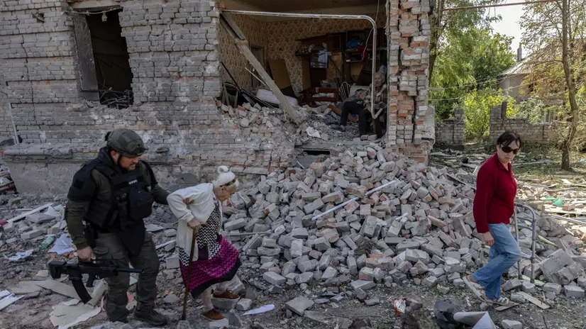epa12385726 An elderly local man (C, rear), who refused to evacuate, sits among the rubble of a damaged building as members of the special Ukrainian police unit 'White Angels' assist an elderly local woman, Vira, 90, evacuate from the frontline city of Kostiantynivka, Donetsk region, eastern Ukraine, 16 September 2025 (issued 17 September 2025), amid the Russian invasion. According to the Ministry of Internal Affairs of Ukraine, more than 6,000 residents, mostly elderly people, remain in Kostiantynivka. The White Angels are a special police unit that provides humanitarian aid, conducts evacuations, and delivers medical assistance in high-risk frontline communities in the Donetsk region. EPA/YEVHEN TITOV