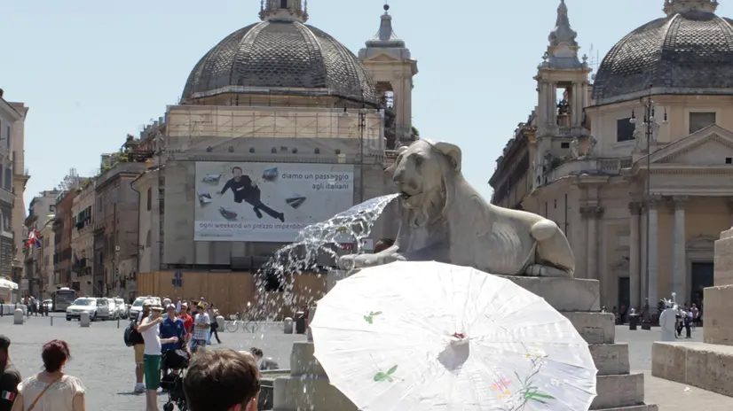 Turisti si riparano dal sole con un ombrellino in piazza del Popolo a Roma il 3 agosto 2012. ANSA/ FABIO CAMPANA