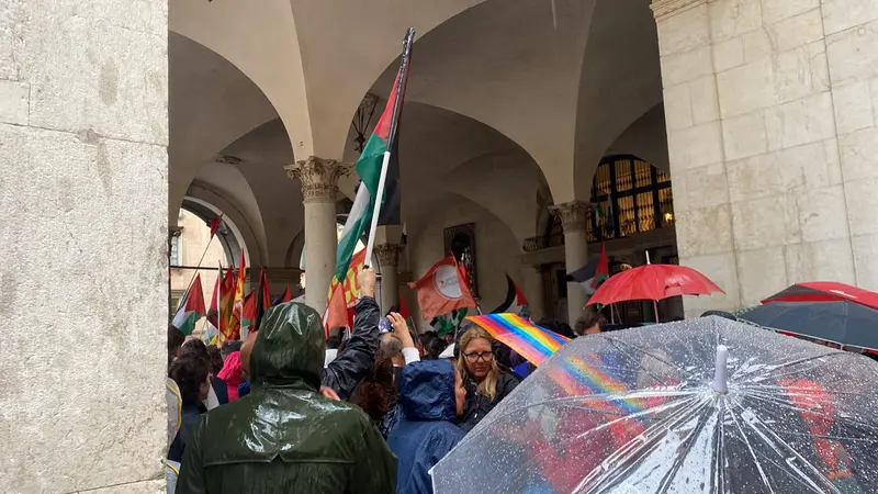 Nonostante la pioggia molti bresciani si sono riuniti sotto il porticato di palazzo Loggia - © www.giornaledibrescia.it