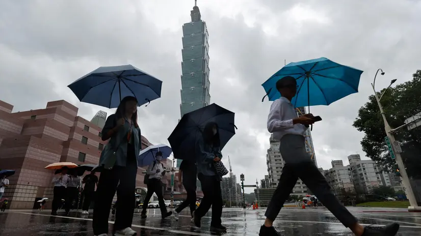 epa12399167 People sheltering under umbrellas cross the street near the Taipei 101 skyscraper building during the afternoon in the wake of Typhoon Ragasa in Taipei, Taiwan, 23 September 2025. At least six individuals were reported injured following the lifting of Typhoon Ragasa's land warning earlier in the day, according to Taiwan's Central Emergency Operation Center (CEOC). Although the Central Weather Administration (CWA) had lifted the land warning, it warned that heavy rain would persist throughout the night across Taiwan, with particularly intense rainfall expected in the eastern regions. EPA/RITCHIE B. TONGO