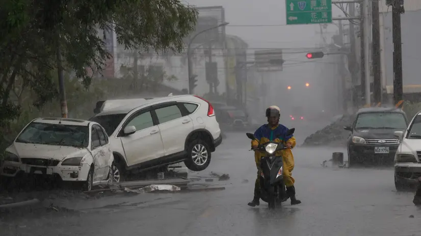 epa12401189 A motorcyclist ride past damaged vehicles on a road in the aftermath of Super Typhoon Ragasa in Guangfu Township, Hualien County, Taiwan, 24 September 2025. At least 14 people have died, 32 were injured and more than 150 are missing in the eastern county after a barrier lake in the mountains overflowed and inundated the township during the typhoon, according to the Ministry of Health and Welfare. EPA/RITCHIE B. TONGO