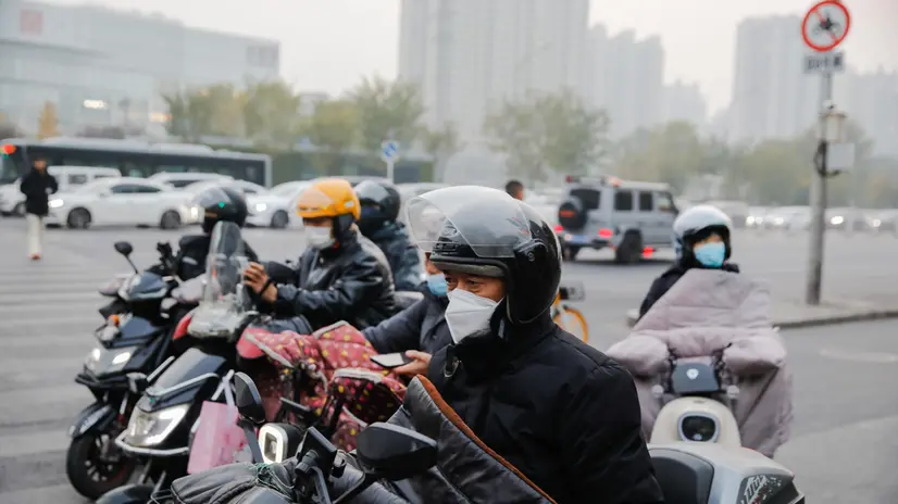epa10987164 People wearing face masks ride scooters on a street amid heavy smog in Beijing, China, 21 November 2023. According to the Beijing Municipal Ecological and Environment Monitoring Center's report, the air quality index of Beijing is 152 on 21 November, with a pollution level of 4, which has reached the moderate pollution standard. EPA/WU HAO
