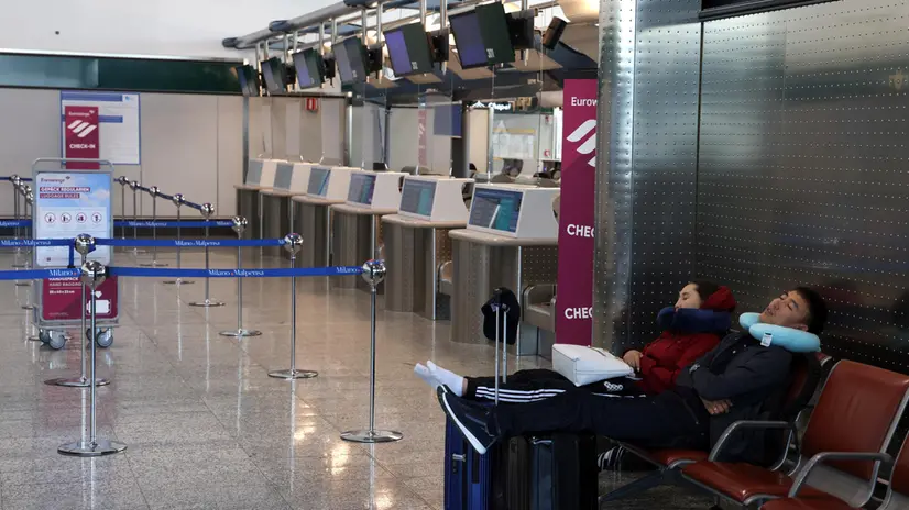Una coppia riposa in attesa di partire dall’aeroporto di Milano Malpensa. Diversi voli sono in ritardo o sono stati cancellati a causa di uno sciopero di 24 ore nel settore del trasporto aereo. Milano 8 Settembre 2023. ANSA / MATTEO BAZZI