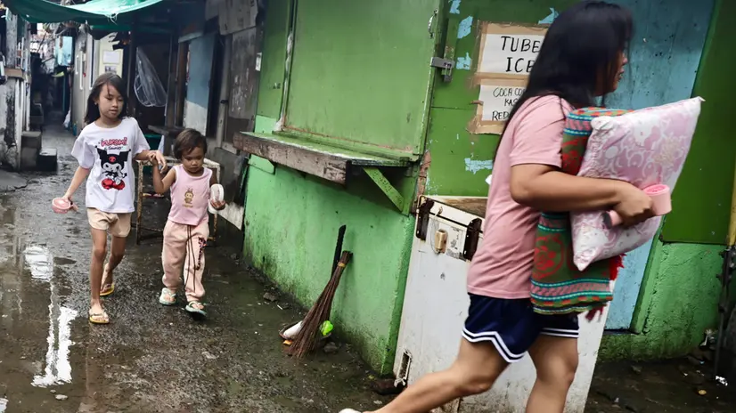 epa12406611 Villagers carry belongings on their way to an evacuation center in anticipation of an approaching storm in Cavite city, Philippines, 26 September 225. Philippine state weather agency warned the public to be on alert for floods, landslides and storm surges as Severe Tropical Storm Bualoi barrels toward central Philippines. EPA/FRANCIS R. MALASIG