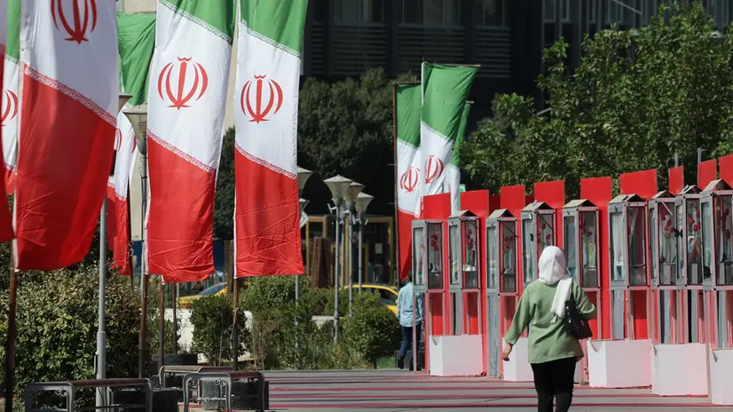 epa12285709 A person walks by a row of Iranian flags on a street in Tehran, Iran, 06 August 2025. Tension between Iran and world powers continues. EPA/ABEDIN TAHERKENAREH