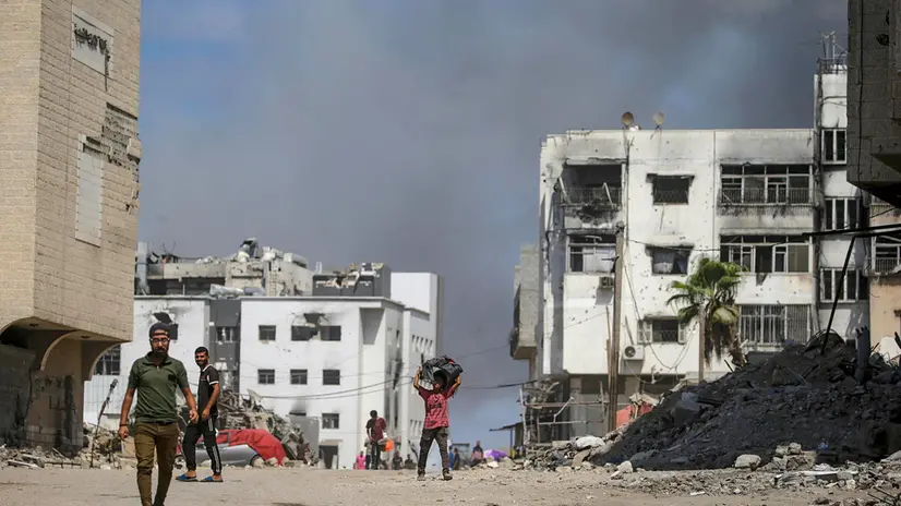 epa12412367 A Palestinian boy (C) walks as smoke rises following an Israeli airstrike around Al-Shifa hospital in Gaza City, Gaza Strip, 28 September 2025. More than 66,000 Palestinians have been killed in the Gaza Strip since October 2023, according to the Palestinian Ministry of Health, and about 1,200 Israelis have been killed since the launch of an Israeli military campaign in response to a cross-border attack by Hamas on 07 October 2023. EPA/MOHAMMED SABER